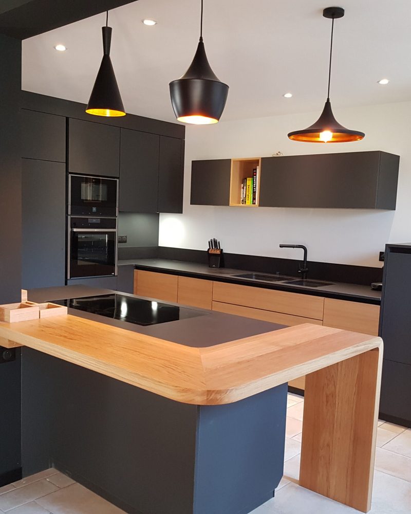 une cuisine noire avec un plan de travail en bois
